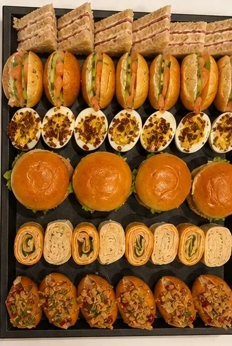 Grand plateau traiteur composé de club sandwichs, mini-burgers, œufs mimosa et wraps roulés