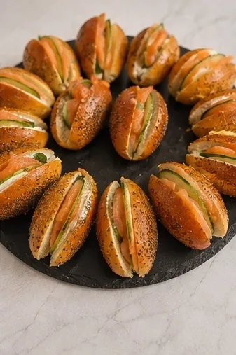 Mini-bagels au saumon fumé et concombre disposés en cercle sur une ardoise